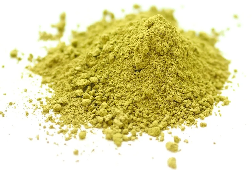 A conical pile of olive-green henna powder on white, product-shot lighting